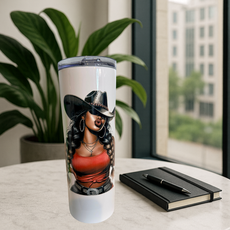 Tumbler with a design of a woman wearing a cowboy hat on a table with a notebook and pen.