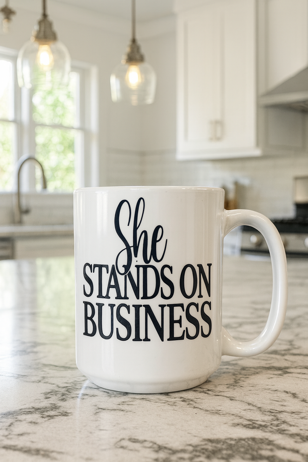 White mug with 'She Stands on Business' text in a kitchen setting